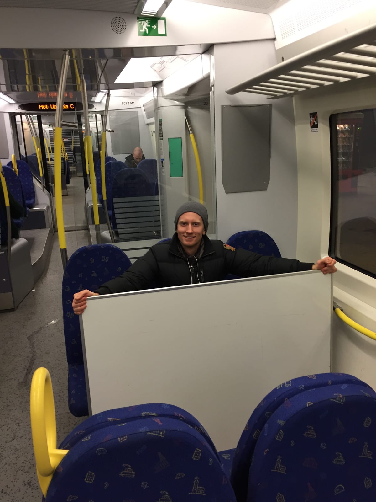Fredrik Brännlund sitter i ett nästan tomt pendeltåg med en nyinköpt whiteboardtavla uppställd mot sätet framför sig