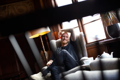 Fredrik Brännlund smiling, leaning back in an armchair with an arm over his head