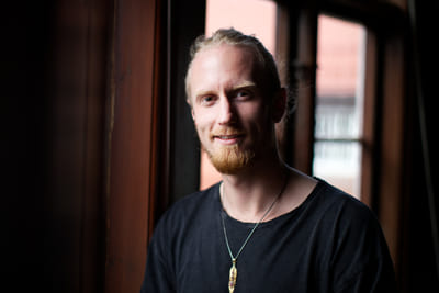 Fredrik Brännlund in a black t-shirt by a window in backlight