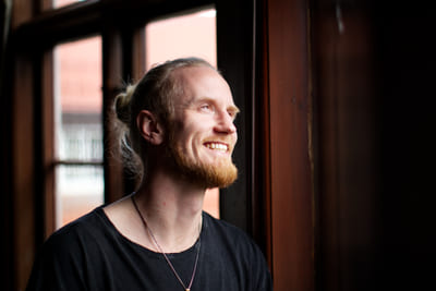 Fredrik Brännlund smiling and looking upward by a window in backlight