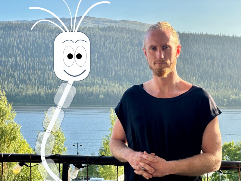Fredrik Brännlund holding up Noa, the nerve cell the game is named after, in front of the mountain and the lake